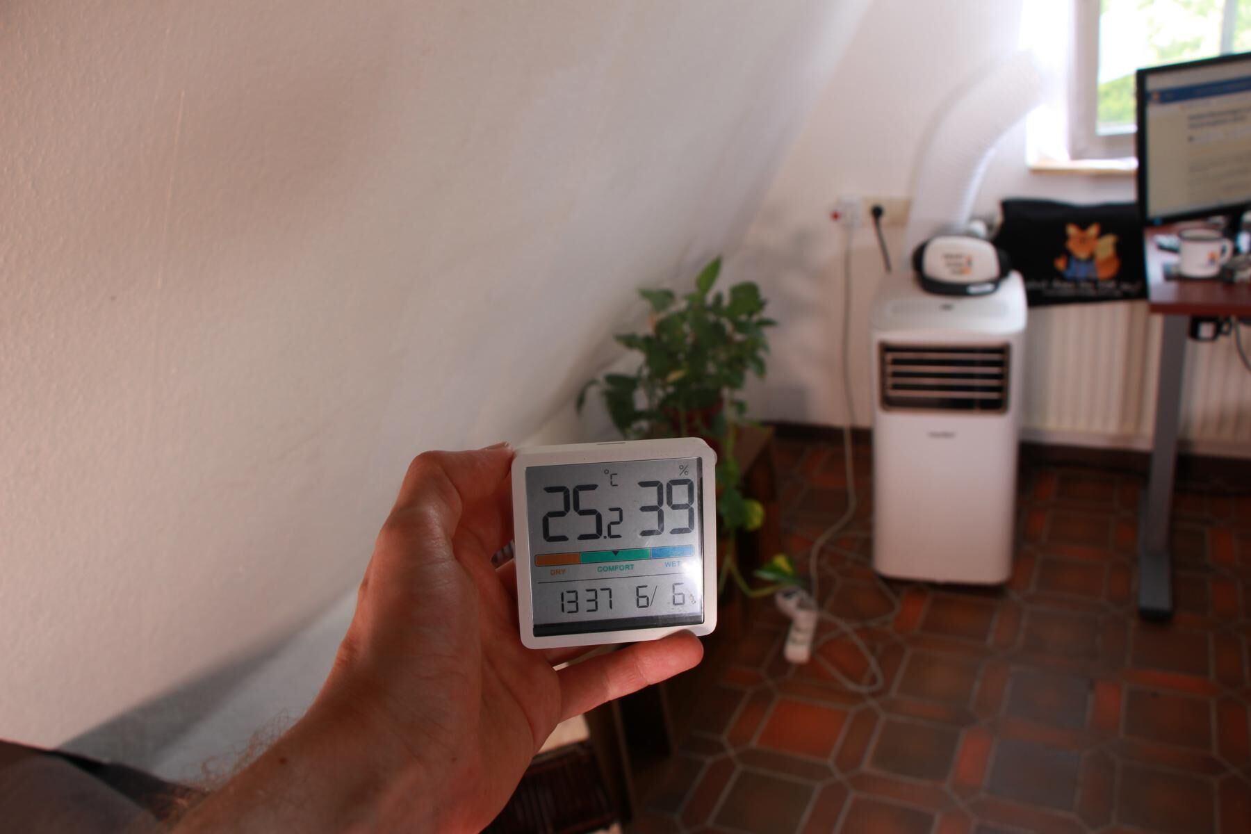 Ein Thermostat wird zum anfang des Kühltests in einigen Metern Abstand zur mobilen Klimaanlage gehalten und zeigt 25,2 Grad Celsius Zimmertemperatur an.