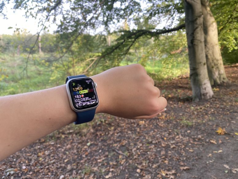 Apple Watch 9 с открытой активностью "Бег" с деревьями на заднем плане